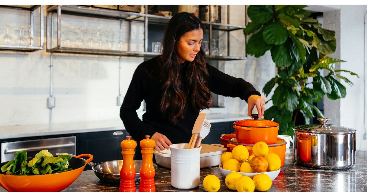 bright eco-friendly kitchen with glass storage jars, wooden utensils, fresh vegetables in reusable produce bags, zero-waste lifestyle in action