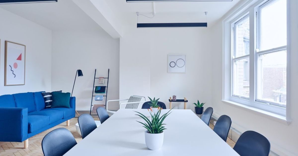 Bright living room with natural sunlight, energy-efficient home design with person adjusting thermostat for savings"