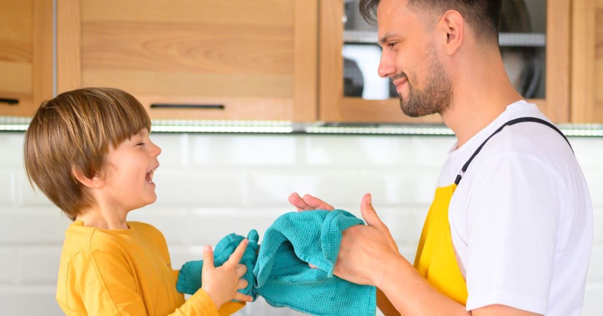 Young girl happily helping with dishes at kitchen sink, learning responsibility through age-appropriate chores