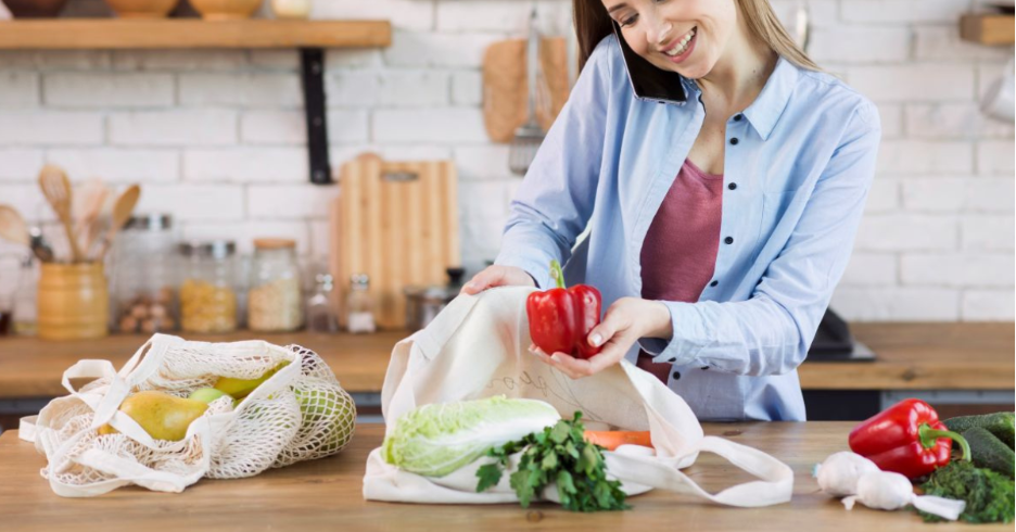 Happy woman with reusable shopping bags and glass jars in bright kitchen, affordable zero waste living starter kit