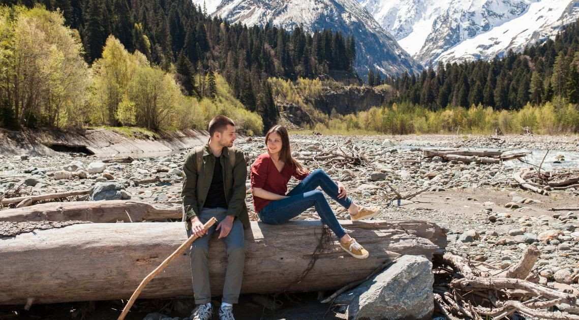 Happy couple hiking in National Park with reusable water bottles and map, zero waste experience gift idea National Park pass