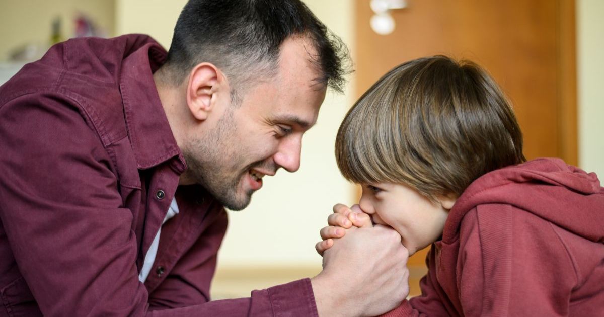 Mother or father kneeling to eye level with young son or daughter, talking warmly and connecting, secure parent-child attachment and emotional connection