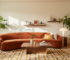 1970s revival living room with rust curved sofa, walnut furniture, mustard rug and graphic artwork